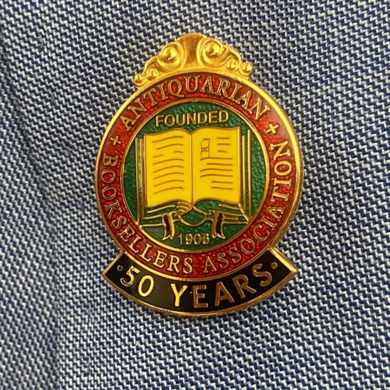 The Antiquarian Booksellers Association 50-year membership badge, gold and enamel, worn on a blue jacket