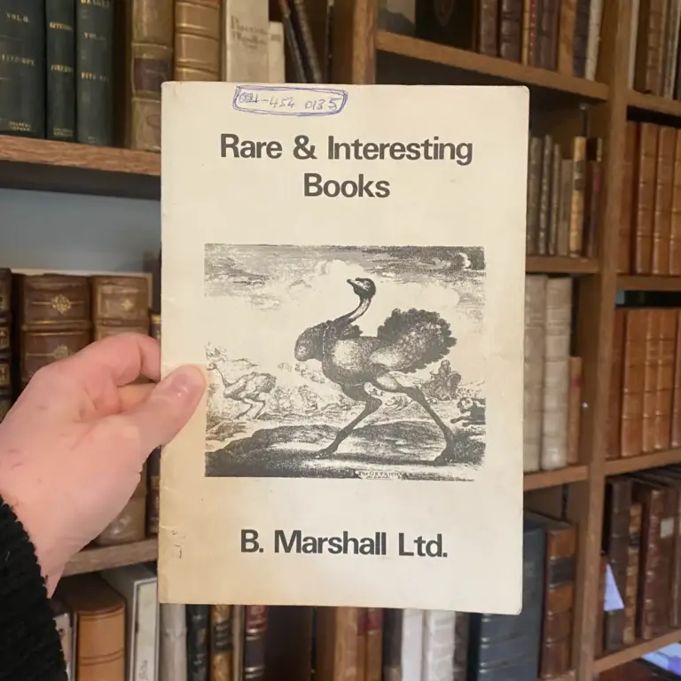 An early B. Marshall Ltd catalogue, Rare & Interesting Books, held in front of bookshelves